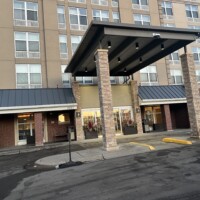 Entrance of a modern hotel with a covered driveway and brick pillars.