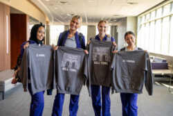 Students pickup Homecoming Sweatshirts in the Anderson Student center leading up to Homecoming Weekend on September 29, 2025, in St. Paul. Nursing students pose for a portrait with sweatshirts. Four people holding St. Thomas sweatshirts.