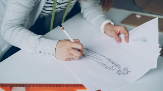 Person sketching fashion design on paper.