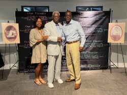 Three well-dressed individuals posing for a photo at an event.